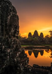 Fototapeta premium Bayon Temple's Sunrise: Stone Faces, Golden Hues, Ancient Majesty