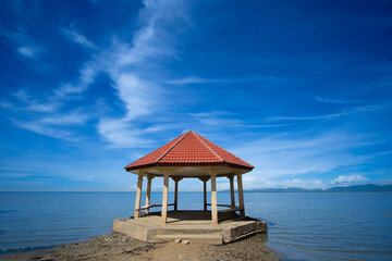 Serene gazebo by calm sea under bright blue sky, perfect for relaxation and enjoying nature beauty. Talumpuk Cape, Pak Phanang, Nakhon Si Thammarat