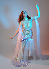 Fantasy studio portrait of a red-haired mermaid faery model wearing a white pearl gown, fairytale...