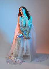 Fantasy studio portrait of a red-haired mermaid faery model wearing a white pearl gown, fairytale...