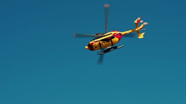 Antibes, France View of a yellow and red emergency helicopter flying on the blue sky
