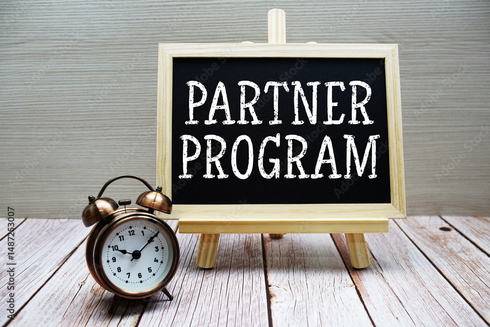 Poster partner program text written on chalkboard with alarm clock on wooden background