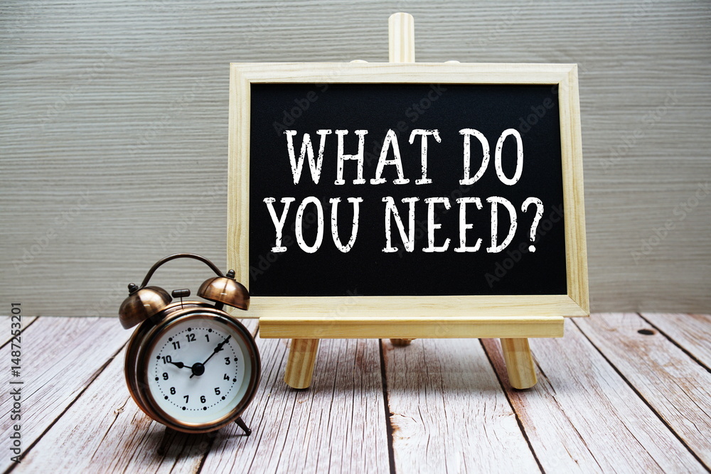 Poster what do you need? text written on chalkboard with alarm clock on wooden background