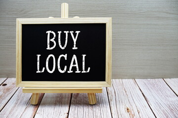 Buy Local text written on chalkboard with easel on wooden background