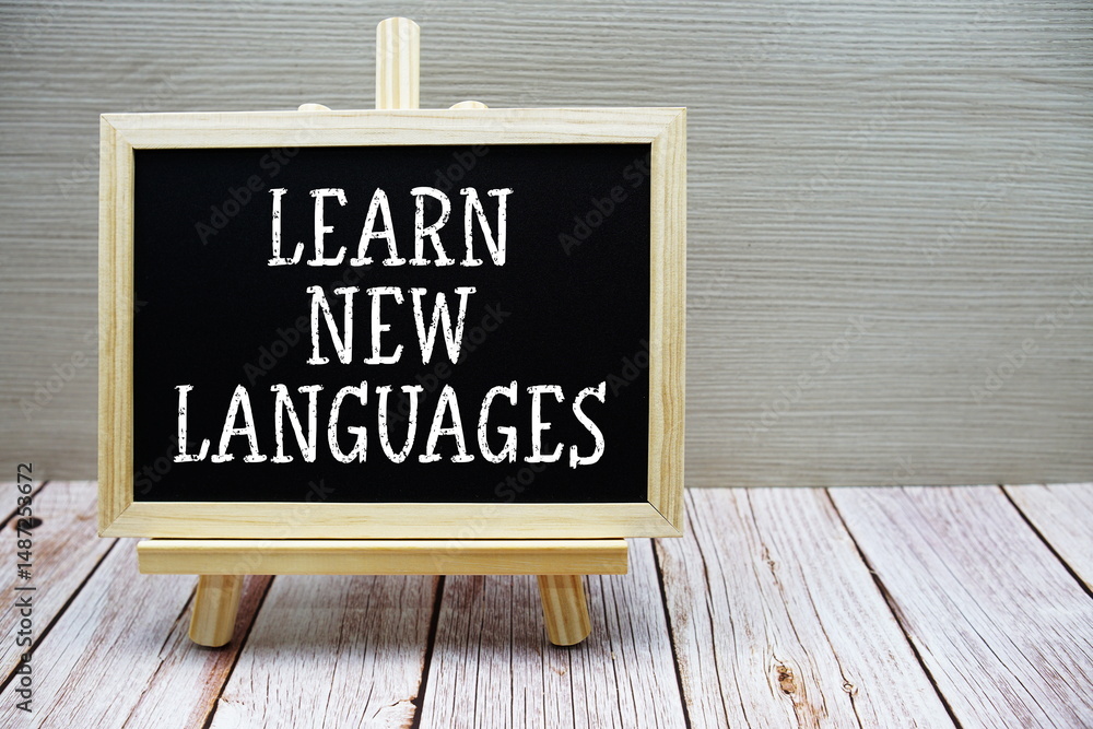 Poster learn new languages text written on chalkboard with easel on wooden background