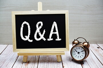 Q and A text written on chalkboard with alarm clock on wooden background