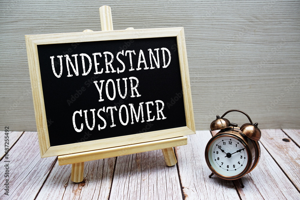 Poster understand your customer text written on chalkboard with alarm clock on wooden background