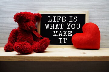 Life Is What You Make It Motivational and Inspiration Quotes on chalkboard with teddy bear on wooden background