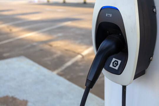 Modern electric vehicle (EV) charger head installed at a designated charging station in an outdoor parking lot, ready for eco-friendly transportation and sustainable energy use.