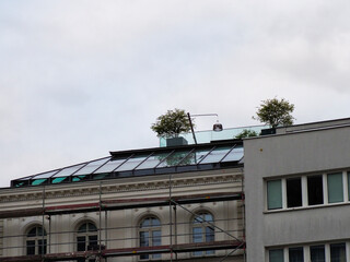 Fototapeta premium Contrast of Historic and Modern Building Architecture with Rooftop Garden Under Cloudy Sky
