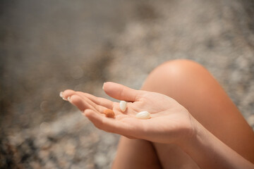 A person is holding a handful of nuts in their hand. The nuts are of different sizes and shapes, and they appear to be almonds. The person seems to be enjoying the nuts and is likely to eat them soon.