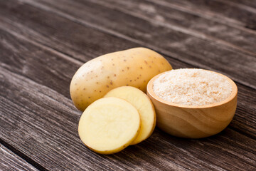 raw potatoes and potato starch on wooden table