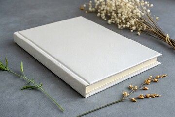 Fototapeta premium White hardcover book with floral decoration on a gray background