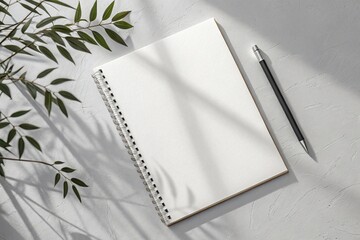Open spiral notebook with blank pages and a pencil on a textured surface with leaf shadows