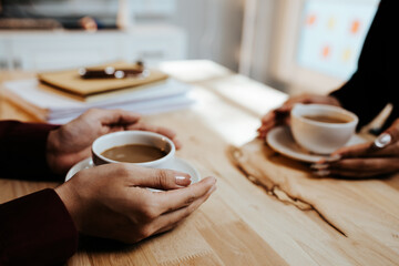 Young adults enjoy coffee and conversation at a cozy café, sharing laughter, bonding, and relaxation in a warm, friendly atmosphere indoors.