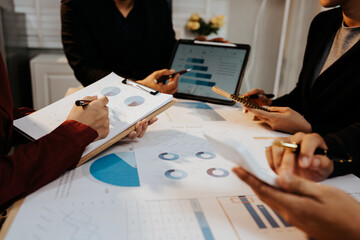 A group of professionals collaborates in an office, analyzing financial graphs and documents to strategize business growth and project success.