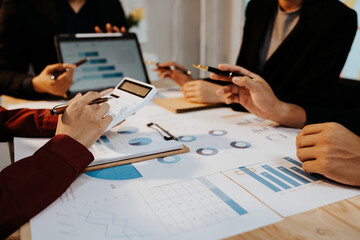 A group of professionals collaborates in an office, analyzing financial graphs and documents to...