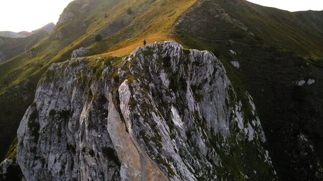 Aerial Backward Shot Of Male Tourist Standing On Green Rock Formation Against Clear Sky - Plav, Montenegro