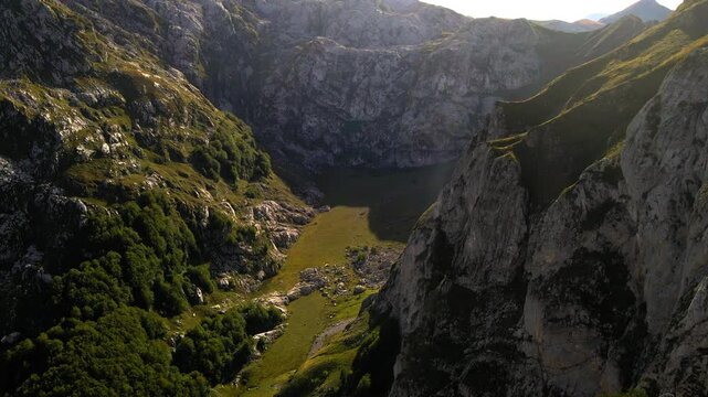 Aerial Tilt Down Scenic Shot Of Green Rock Formations Against Clear Sky, Drone Flying Forward On Sunny Day - Plav, Montenegro