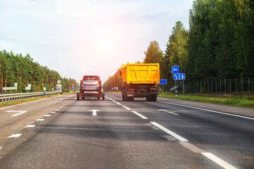 Transporting an SUV car on a carriage along a country road in the summer against the backdrop of the sun. Carriage rental services. Copy space for text