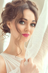 Close-up portrait of a luxurious bride in a wedding dress in the morning in a chic interior. wedding makeup and hairstyle. Beautiful face with big green eyes.