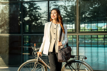 Young Asian business woman riding bicycle in urban city. Sustainable save energy lifestyle. Commute...