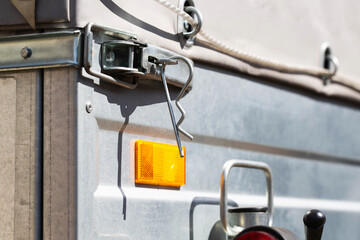 orange reflector on the side of a galvanized trailer body, close-up