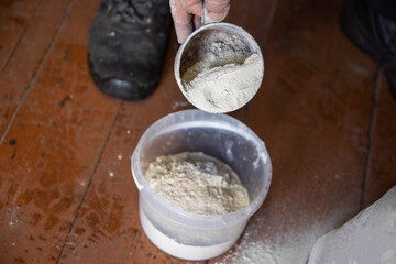 Dolomite flour in a mug against a bucket, deoxidizing the soil in the garden. Increasing crop...