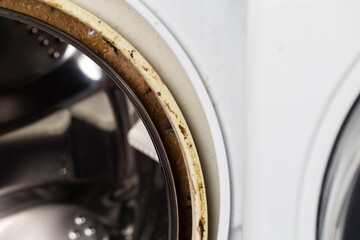 Dirt, mildew and mold in the hatch seals of the washing machine. Unsanitary and unpleasant smell. Cleaning and repairing stains in the washing machine, close-up