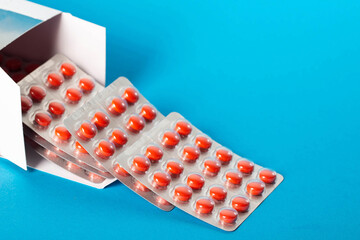 Blister pack of red pills on blue background. Concept of vitamins magnesium, minerals and calcium in pharmaceuticals. Copy space for text, close-up