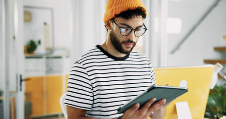 Fototapeta na wymiar Creative, man and reading on tablet in office for research, schedule update and review newsletter. Male journalist, digital and editing article, story information and feedback of magazine publication