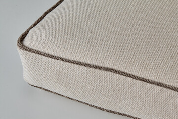 Beige cushion with brown border highlighting fabric texture and weaving detail