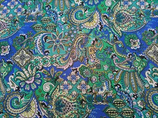 Paisley patterned fabric detail background, featuring curved, teardrop shaped motifs of Persian origin with vibrant colors like blue and green, texture