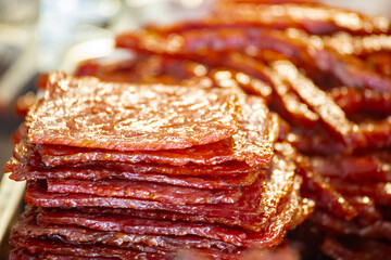 a pile of reddish and glossy dried meat is displayed on a stall