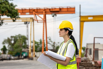 Female civil engineer or architecture is using a blueprint plan to check for the progress of...