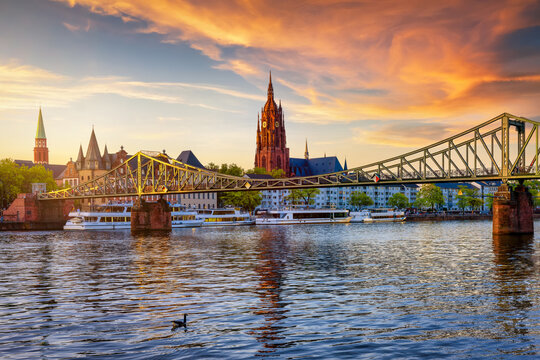The skyline of Frankfurt am Main, Germany, with Eiserner Steg bridge and Kaiserdom church during a golden summer sunset
