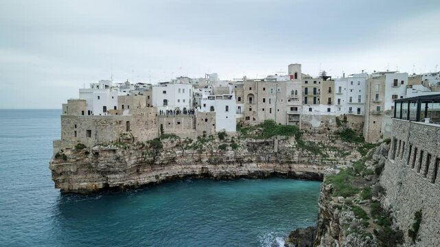 View of the ancient Apulian seaside village overlooking the sea and built on a rocky ridge and cliff near the beach of Lama Monachile. Fast moving clouds on a Day-to-Night 4K Timelapse video.