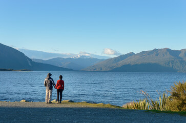 Couple holding hands and enjoying the views of Lake Brunner. West Coast. South Island. New Zealand.