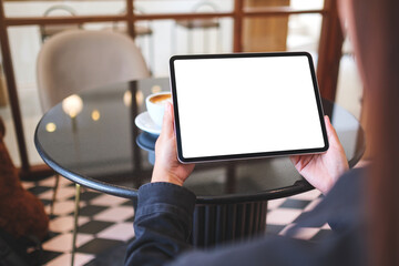 Mockup image of a woman holding digital tablet with blank white desktop screen in cafe