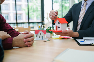 Couple consulting with a real estate agent in a cozy office, reviewing home-buying options with...