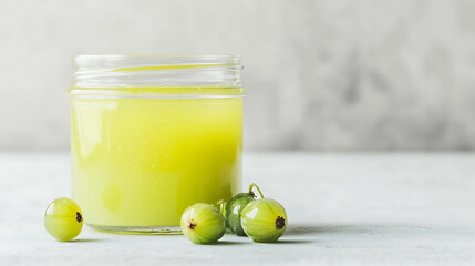 Jar of green juice with fresh gooseberries beside it.