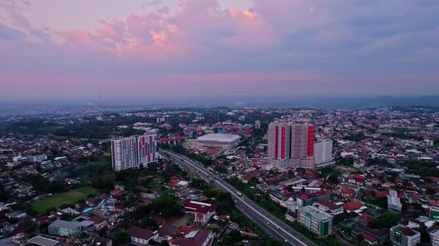 Drone view of tembalang regency in semarang city with beautiful purple sunset sky. Aerial view of auditorium, apartment, and toll road in tembalang regency 