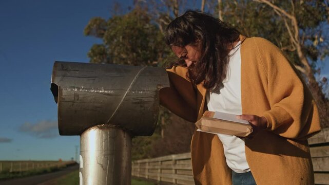 Woman collecting mail from a rural mailbox outdoors