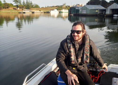Smiling Young Man Steering Outboard Boat on River