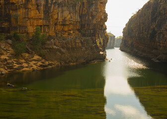 Distant canoeists on still water in deep gorge with cliffs