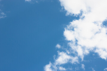 Snowy white and fluffy clouds in a bright blue sky with an empty place. A template for the design with copy space. Clouds form interesting silhouettes and patterns.
