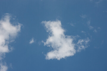 Snowy white and fluffy clouds in a bright blue sky with an empty place. A template for the design with copy space. Clouds form interesting silhouettes and patterns.