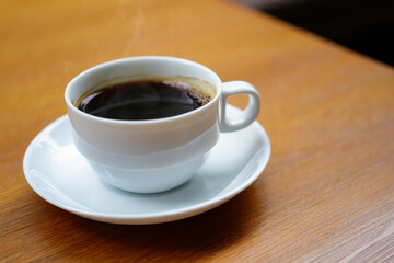 Fototapeta premium Aromatic Coffee: A close-up shot of a steaming cup of coffee, presented on a saucer. Capturing a moment of warmth, invigoration and peaceful beginning.