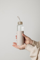 Woman's hands holding reusable eco-friendly bottle with fresh water in it. Healthy lifestyle, bottle mock up.