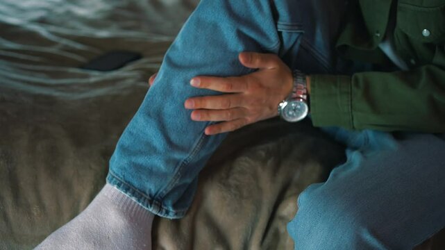 Pain in the calf muscle.
A man massages a muscle on his leg.
A young guy sitting on the couch has a leg injury.
A man touches the calf on his leg
